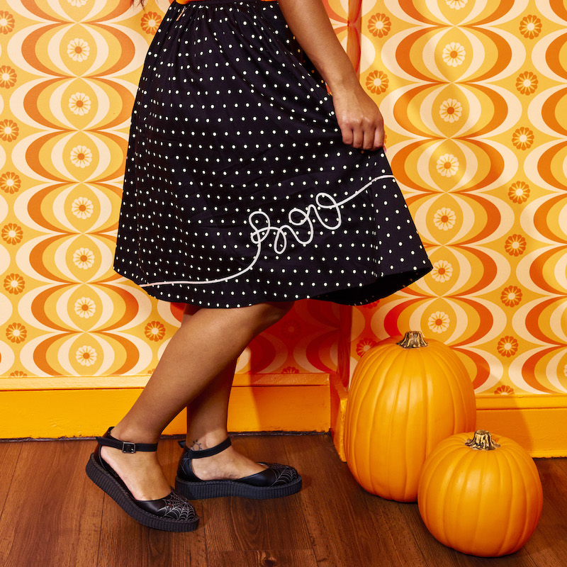 Side shot of a woman wearing the Pumpkin Balloon Sandy Skirt to show off the image of how the balloon strings spell out the word "Boo" 
